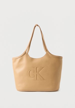 Tan læder skuldertaske med præget "cK" logo foran og to lange remme til at bære.
