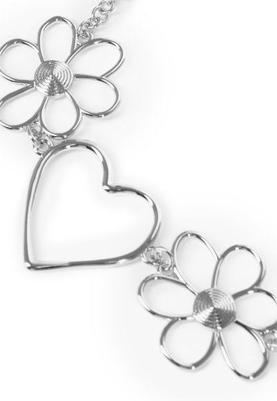 Sølvarmbånd med to blomsterformer og et hjerte. Blomsterne har teksturerede midtpunkter; hjertet har en glat omrids.