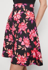 Jupe évasée en tissu noir ornée de grandes fleurs roses et violettes, avec une texture lisse et une taille ajustée pour un ajustement structuré.