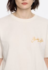 Crème katoenen t-shirt met een ontspannen pasvorm, met een gele geborduurde logo "Bimba y Lola" op de linkerborst.