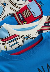 Trois t-shirts en coton avec des imprimés éclatants : camion de pompiers rouge, ambulance et bleu uni avec un col rouge. Texture douce, col en jersey.