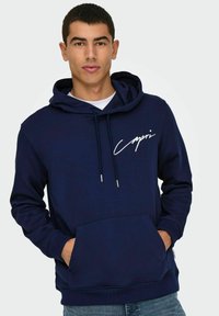 Navyblaue Kapuzenjacke mit Kängurutasche, Kordelzügen und weißem Grafiktext. Hergestellt aus weichem Material mit lässiger Passform und gerippten Bündchen.