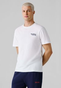 Biele bavlnené tričko s okrúhlym výstrihom, s tmavomodrým logom "RED BULL RACING" na ľavej strane hrudníka. Krátke rukávy, voľný strih.