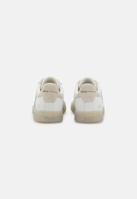 White sneakers with a smooth leather upper and suede accents. Clear rubber sole with branding on the heel and quarter panel.