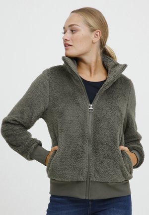 Veste en polaire vert olive à fermeture éclair avec un col haut, des poignets côtelés et des poches, présentant une texture douce et un design décontracté.