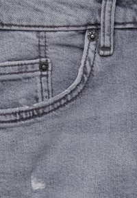 Tejido de denim en gris claro con una textura sutil. Presenta un bolsillo frontal, costuras, un botón de metal y una zona desgastada cerca del bolsillo.