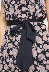 Květinové šaty s tmavě námořnickým pozadím, světle růžovými růžemi, texturovanou tkaninou a odpovídajícím páskem na zavázání v pase.