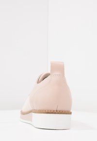 Scarpa in pelle rosa chiaro con punta rotonda, suola bianca e tacco basso; presenta dettagli di cucitura e una linguetta sul retro.