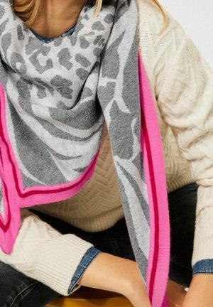 Châle gris à motif animalier, bordé de rose vif. Tissu doux qui tombe élégamment autour du cou, complété par un pull texturé.