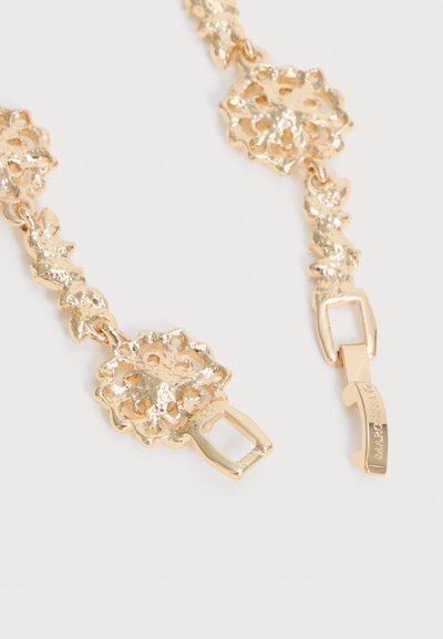 Χρυσό κολιέ με αλυσίδα λουλουδάτο σχέδιο, με περίπλοκους υφασμένους κρίκους και ορθογώνιο κούμπωμα χαραγμένο με το όνομα μιας μάρκας σε λευκό φόντο.