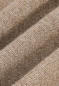 Teksturowany, beżowy materiał o plecionym wzorze i miękkim wykończeniu, ukazujący różnice w grubości nitek oraz lekko błyszczącą powierzchnię.
