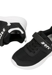 Paire de baskets pour enfants noires et blanches en tissu mesh, bande auto-agrippante étiquetée BRTK, semelles blanches rembourrées sur fond blanc.