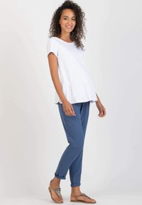 White short-sleeve peplum top paired with blue tapered pants. The outfit features soft fabrics and a casual fit, ideal for comfortable wear.