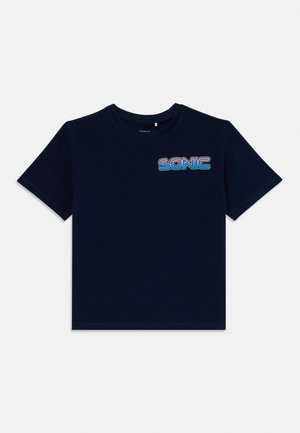 T-shirt de algodão azul-marinho com mangas curtas, apresentando um gráfico multicolorido "SONIC" em fonte retro no lado esquerdo do peito.