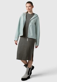 Giacca a zip con cappuccio blu chiaro, abito grigio a coste con spacco laterale e stivali alla caviglia grigi con suola spessa e dettagli neri.