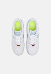 Een paar witte Nike Air Force 1-sneakers met lichtblauwe accenten, witte veters en neon groene binnenzolen, vanuit bovenaf bekeken op een witte achtergrond.