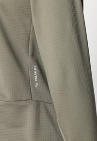 Olivgrüne Jacke aus strukturiertem Stoff. Verfügt über ein Polarlite-Logo in der Nähe der Naht, das ein körperbetontes Design und eine glatte Oberfläche zeigt.