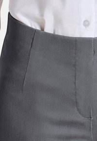 Grijze op maat gemaakte broek met een gladde textuur, voorzien van een vlakke voorkant, subtiele stiksels en zijzakken, gecombineerd met een wit overhemd met knopen.