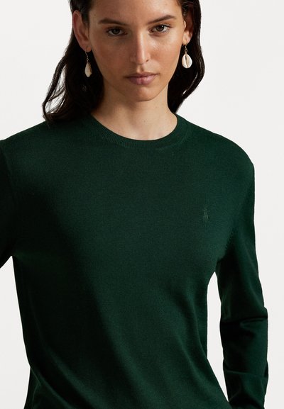 Green knit sweater with a round neckline, long sleeves, and a subtle logo on the chest. Smooth texture and lightweight fabric.