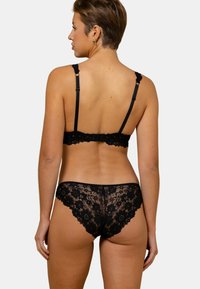 Ensemble de lingerie en dentelle noire avec des motifs floraux, des bretelles ajustables et une délicate bordure festonnée sur le soutien-gorge et le slip.