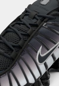 Sapatilha da Nike com um design em degradê de cinza escuro para claro, upper em malha, sola em borracha e o destacado logótipo swoosh preto na lateral.