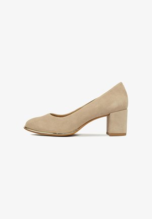 Zapato de salón de ante beige para mujer con punta redonda, ribete dorado en el borde de la suela y tacón cuadrado sobre fondo blanco.