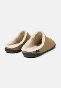 Pantofole in pelle marrone con una morbida fodera in pelliccia bianca, apertura sul retro e suola in gomma nera. Presenta un bordo cucito e un'etichetta del marchio sul lato.