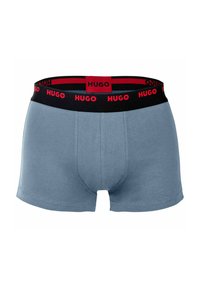 Men's boxer shorts in light blue cotton, featuring a black elastic waistband with red "HUGO" branding. Classic mid-length design with smooth texture.