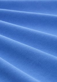 Helles blaues Material mit einer strukturierten, gerippten Oberfläche, die Falten und glatte Linien zeigt und ein wellenartiges Muster bildet.