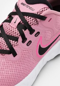 Le sneakers Nike Renew rosa presentano una tomaia in mesh traspirante, lacci neri e un distintivo design con il logo swoosh nero. I pannelli testurizzati aggiungono dettagli.
