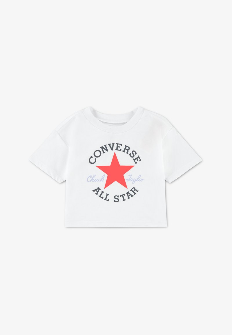 T-shirt bianca corta con maniche corte, caratterizzata da una grande stella rossa e dalla scritta "CONVERSE ALL STAR" in nero, con "Chuck Taylor" in azzurro.
