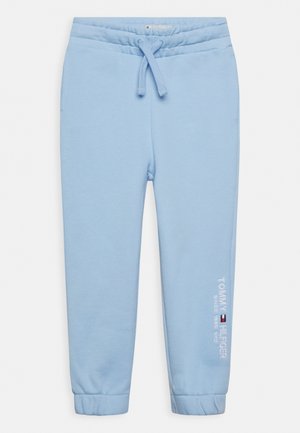 Jasnoniebieskie spodnie dresowe dla małego dziecka z elastycznym pasem i ściągaczami, sznurkiem oraz białym logo "Tommy Hilfiger" na lewej nogawce.