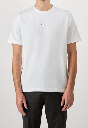 T-shirt blanc à manches courtes en coton avec un col rond et un logo "BOSS" noir sur la poitrine. Design simple et épuré, texture lisse.