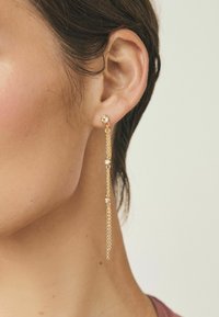 Gold-tone earrings featuring a round stud with a chain dangling that includes small crystal accents, creating a layered effect.