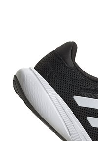 Baskets noires de sport avec une tige en mesh, semelle en caoutchouc blanche et trois rayures blanches distinctives sur le côté. Présente une finition texturée.