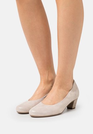 Décolleté in suede beige chiaro con punta arrotondata e tacco basso impilato, caratterizzati da una finitura liscia e un leggero lucido.