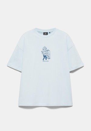 T-shirt azzurro chiaro a maniche corte con una piccola grafica blu navy di una persona che trasporta bagagli impilati e testo "WEEKEND LUGGAGE" al centro davanti.