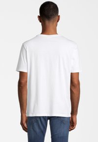 Weißes Baumwoll-T-Shirt mit kurzen Ärmeln, Rundhalsausschnitt und glatter Textur. Von hinten betrachtet, kombiniert mit blauen Jeans.