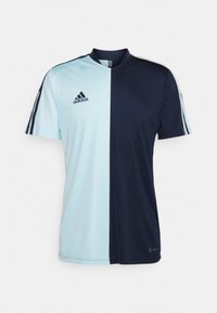 Jersey de Adidas de manga corta dividido por la mitad: azul claro a la izquierda, azul oscuro a la derecha. Cuenta con un cuello y rayas en los laterales.
