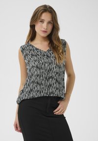Débardeur sans manches avec un décolleté en V, arborant un motif rayé vertical noir et blanc. Le tissu semble léger et fluide.