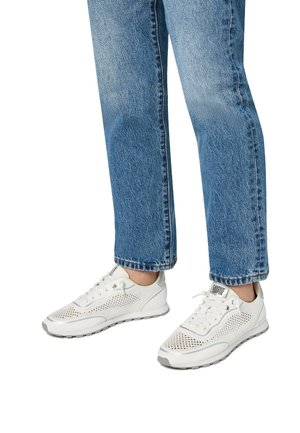 White athletic sneakers with mesh panels, lace-up design, and gray accents, paired with loose-fitting blue denim jeans.