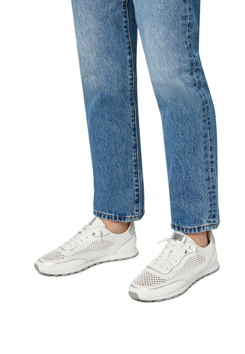 Weiße Sportsneakers mit Netzpaneelen, Schnürdesign und grauen Akzenten, kombiniert mit lässigen, weit geschnittenen blauen Jeans.