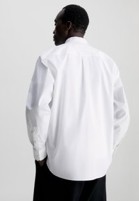 Witte langesleeve shirt gemaakt van zachte katoen, met een klassieke kraag, knoopsluiting bij de manchetten en een relaxte pasvorm. Gedetailleerde achterkant.