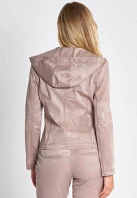 Blush pink jacket with a hood, featuring a textured palm leaf pattern. Fitted design with subtle seams and a smooth finish.