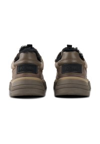 Brune lædersneakers med en tekstureret overflade, der har et sort fur-detalje ved hælen og en gummisål med kontrasterende grå detaljer.