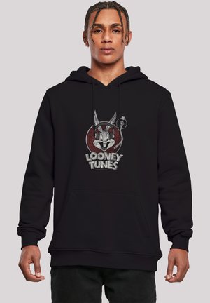 Sort hættetrøje med et motiv af Bugs Bunny inde i en rød cirkel med teksten "Looney Tunes." Materialet ser blødt ud, og der er en frontlomme.