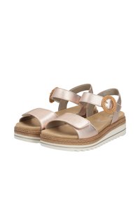 Metallische roségouden sandalen met twee brede banden, een geweven cirkelaccent en een gevoerd voetbed op een witte, textuurrijke zool.