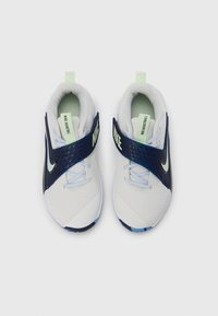 Valkoiset ja laivastonsiniset lenkkarit verkkopäällisellä, säädettävällä hihnalla, vaaleanvihreillä yksityiskohdilla ja sinisellä kuvioidulla pohjalla. Brändäys hihnassa ja kielen päällä.