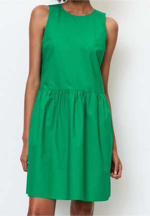 Mouwloze felgroene jurk met gerimpelde taille en ronde hals, gedragen door een persoon met een middelbruine huidskleur.