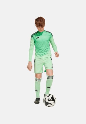 Tenue de soccer athlétique verte avec un haut à manches longues texturé, un short assorti et des chaussettes rayées, accompagné d'un ballon de soccer noir et blanc.